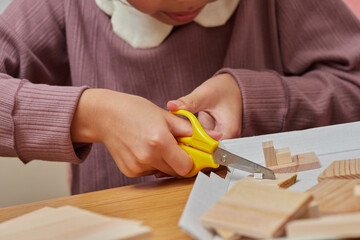 家で木材の端材を使って工作宿題をしている小学生の女の子の様子