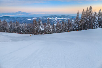 Fototapeta na wymiar Empty ski slope in the forest at dawn, Romania
