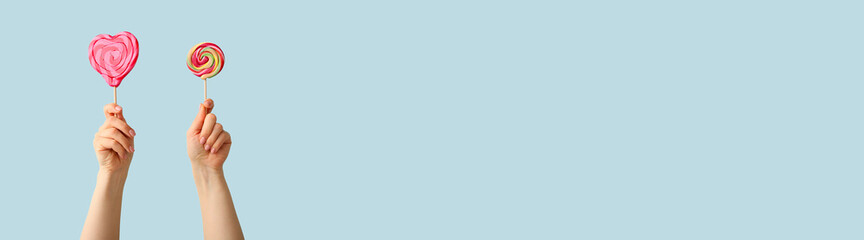 Hands with sweet lollipops on color background with space for text