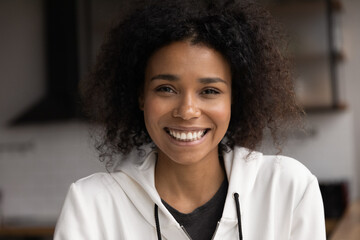 Close up head shot beautiful African woman look at camera having wide toothy smile natural afro curly hair. Profile picture video call participant, portrait of successful entrepreneur female concept