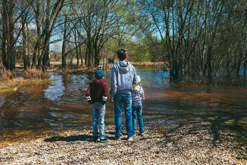 a man with his daughter and son are standing by the flooded river on a rocky beach