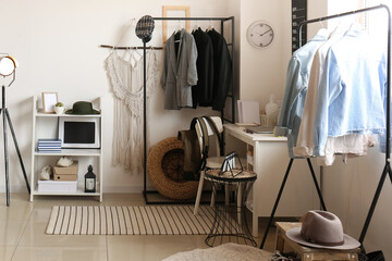 Interior of room with modern workplace and stylish female clothes