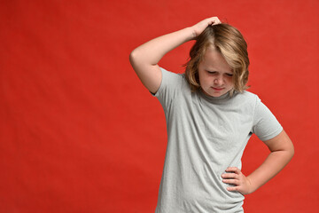 Pensive serious teenager in a white t-shirt on a red background