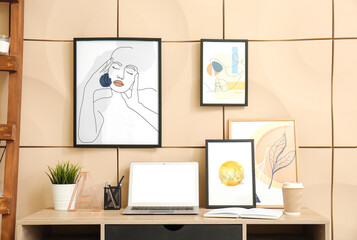 Modern workplace with pictures near color wall