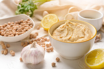 Bowl with tasty hummus and ingredients on light background