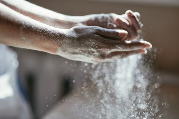 Fototapeta premium Motion picture - sifting flour by hand, women's hands close-up in backlight