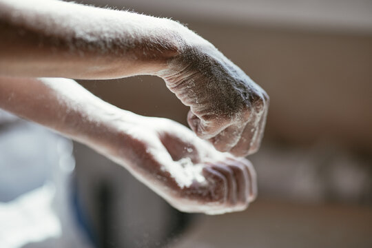 Hands in flour with backlighting on a blurry background, close-up photo