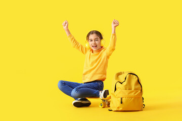Happy little girl listening to music on color background