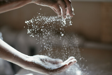 Fototapeta premium Girl scattering flour in the air, close-up photo of hands