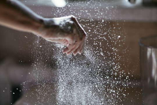 Glowing particles of flour in the air and a woman's hand close-up, photo of a hand in motion, blurred background