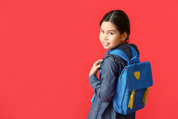 Cute little girl with stylish school backpack on color background