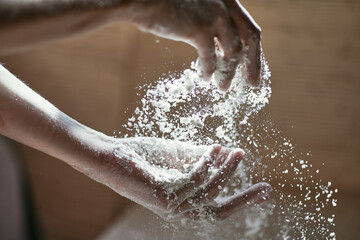 Fototapeta premium Motion picture - sifting flour by hand, women's hands close-up in backlight