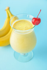 Glass of tasty banana daiquiri cocktail and fruits on color background