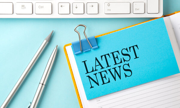 LATEST NEWS text on sticker on the blue background with pen and keyboard