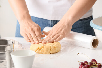 Obraz na płótnie Canvas Woman with raw dough for cherry pie at table