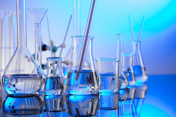 Laboratory investigations. Glass tubes and beakers on blue background.