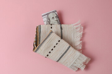 Money and white fringed napkin on pink background. The one hundr