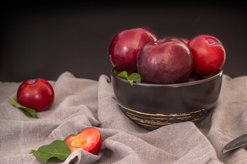 Still life with large black plums in a deep plate