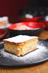 One piece of cheesecake served with s lot of different dessert in plates on a wooden table.