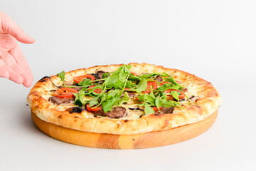 Tasty pizza with meat, mushrooms, tomatoes and basil isolated on white. Hands reaching for pizza.