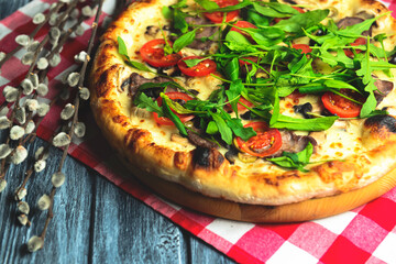 Rustic tasty pizza with meat, mushrooms, tomatoes and basil. Over wooden table, photo in dark tones.