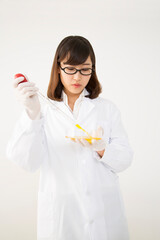 シャーレにピペットで試薬を注ぐ白衣を着た若い女性