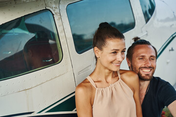 Portrait of pleased people being taken near little airplane