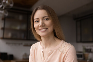 Head shot portrait young Caucasian 35s woman sit in domestic kitchen smile looks at camera. Video call participant profile picture, videoconferencing event, personal or business communication concept © fizkes