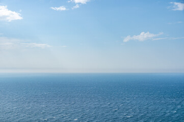 Fototapeta na wymiar The sea and clouds, through which the sun's rays shine through, reflecting on the surface of the sea on a warm summer day. can be used as a nature background or landscape.