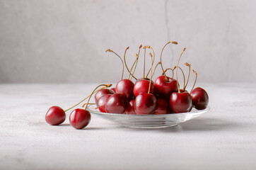 Fresh cherries on a saucer. Harvest of red cherries. Light background