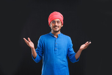 Young indian farmer giving expression on dark background.