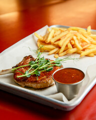 Grilled steak with french fries, tomato sauce and fresh arugula. Concept for a tasty and hearty meal.