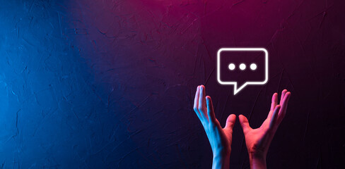 Hand on neon background holding a message icon, bubble talk notification sign in his hands. Chat...