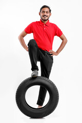 Handsome young male mechanic with new tires isolated on white background.