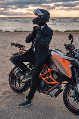 Fototapeta na wymiar Cool businessman with motorcycle helmet posing against seascape