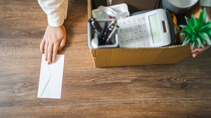 Fototapeta na wymiar Business woman sending resignation letter and packing Stuff Resign Depress or carrying business cardboard box by desk in office. Change of job or fired from company