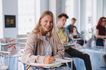 Portrait of group of university students sitting in classroom indoors, studying.