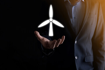 Businessman holding an icon of a windmill that produces environmental energy. Dark background