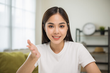 Young asian woman looking at camera video conference online sitting in living room at home. Business Woman looking at screen Meeting on social media live steam. Work, learning from home.