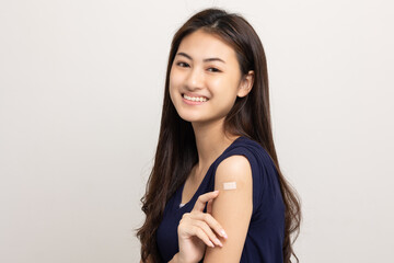 Vaccination. Young beautiful asian woman getting a vaccine protection the coronavirus. Smiling happy female showing arm with bandage after receiving vaccination. On isolated white background.