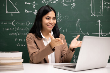 Young asian teacher woman sitting using laptop video conference with student. Female teacher...