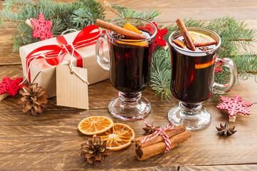 Christmas mulled red wine with spices and oranges on a wooden rustic table. Traditional hot drink...