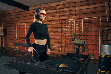 Focused woman in safety glasses standing at a shooting club