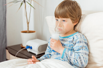 Boy with a respiratory syncytial virus, inhaling medication through an inhalation mask. Flu,...