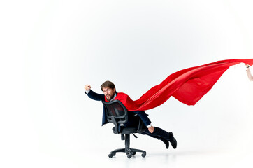 Fototapeta na wymiar man with red cloak in office chair manager superhero studio