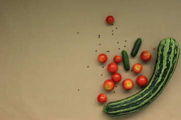 Tomatoes, cucumbers and zucchini on a brown background