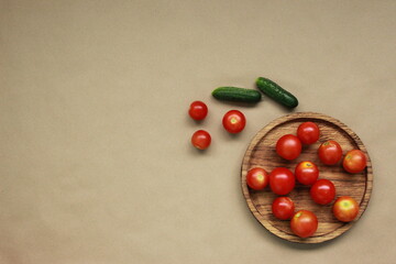 Naklejka na ściany i meble Wooden plate with tomatoes and cucumbers on brown background