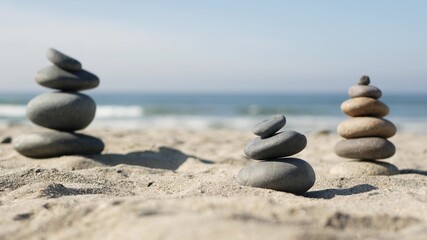 Fototapeta na wymiar Rock balancing on ocean beach, stones stacking by sea water waves. Pyramid of pebbles on sandy shore. Stable pile or heap in soft focus with bokeh, close up. Zen balance, minimalism, harmony and peace