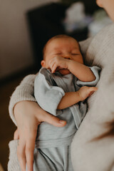 close up portrait of a beautiful sleeping baby in the arms of mom in the bedroom in daylight