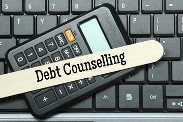 laptop keyboard, calculator, ice cream stick with the word debt counseling